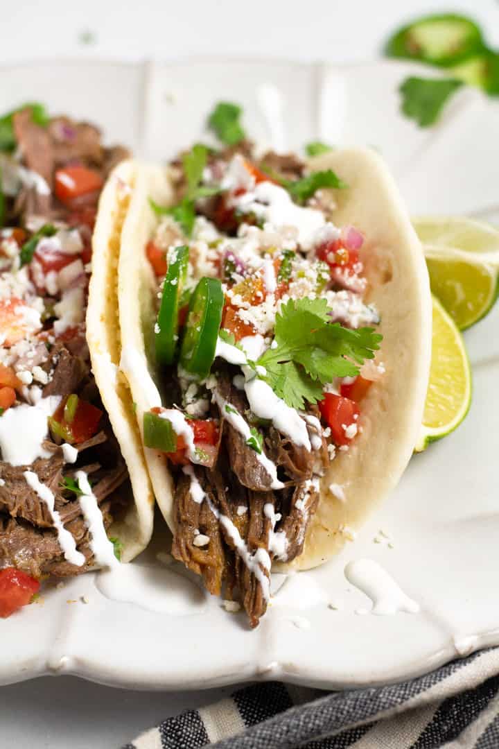 Close up shot of a barbacoa beef platter garnished with fresh cilantro and sour cream