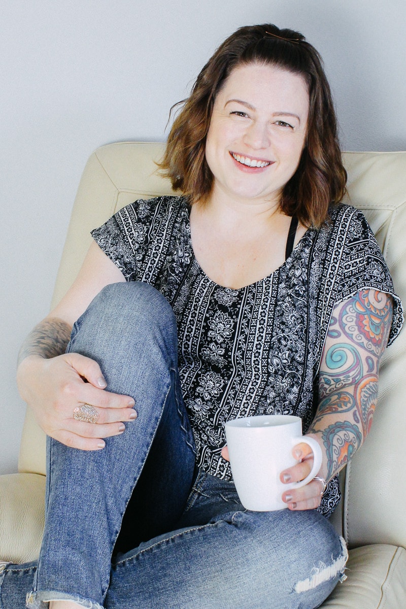 Photo of a person sitting on a chair holding a cup of coffee and smiling