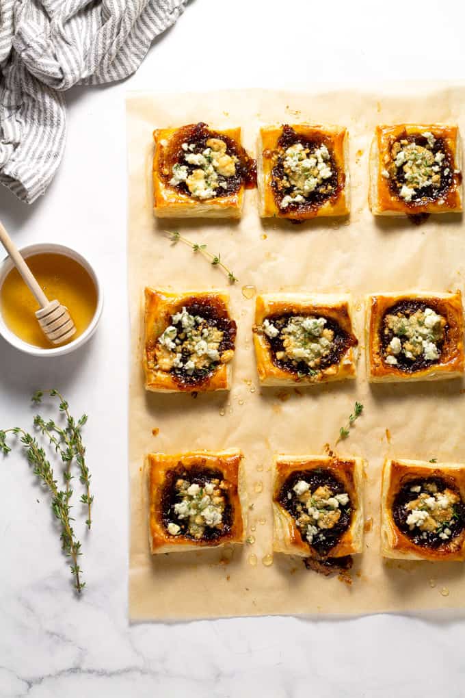 Overhead shot of parchment paper with caramelized onion puff pastry tarts on top of it
