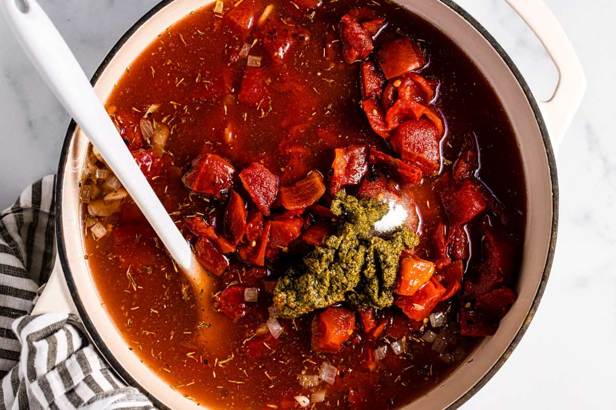 Large white pot filled with ingredients to make creamy vegan tomato soup 