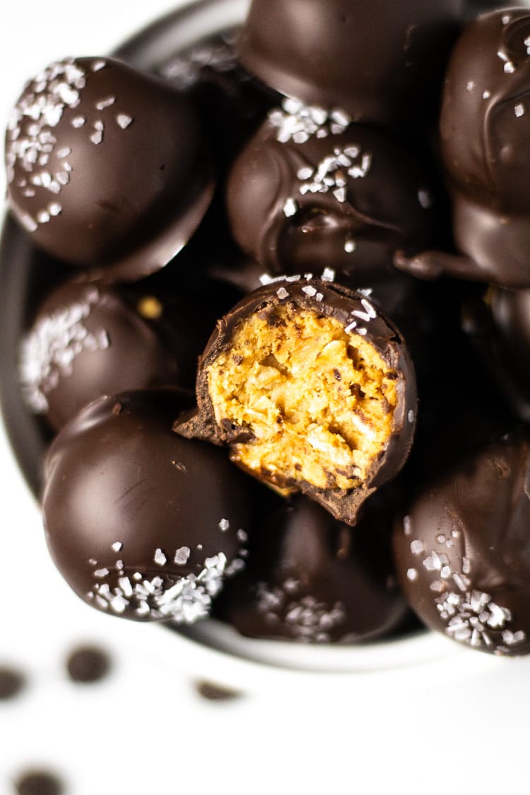 Overhead shot of a white bowl filled with peanut butter balls with a bite taken out of one