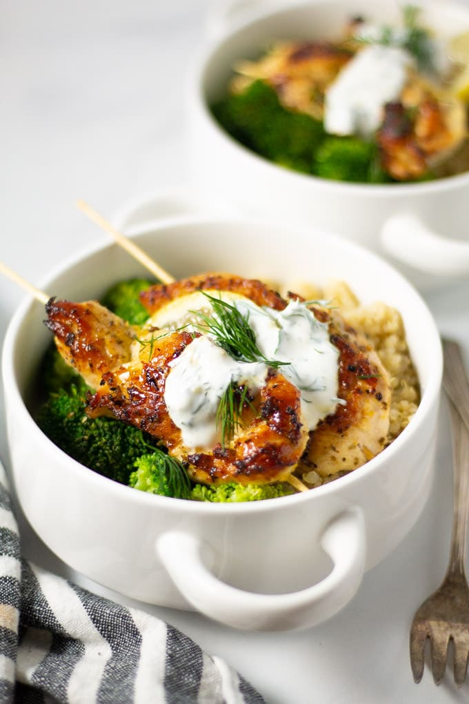 White bowl filled with Greek chicken kebabs quinoa and broccoli