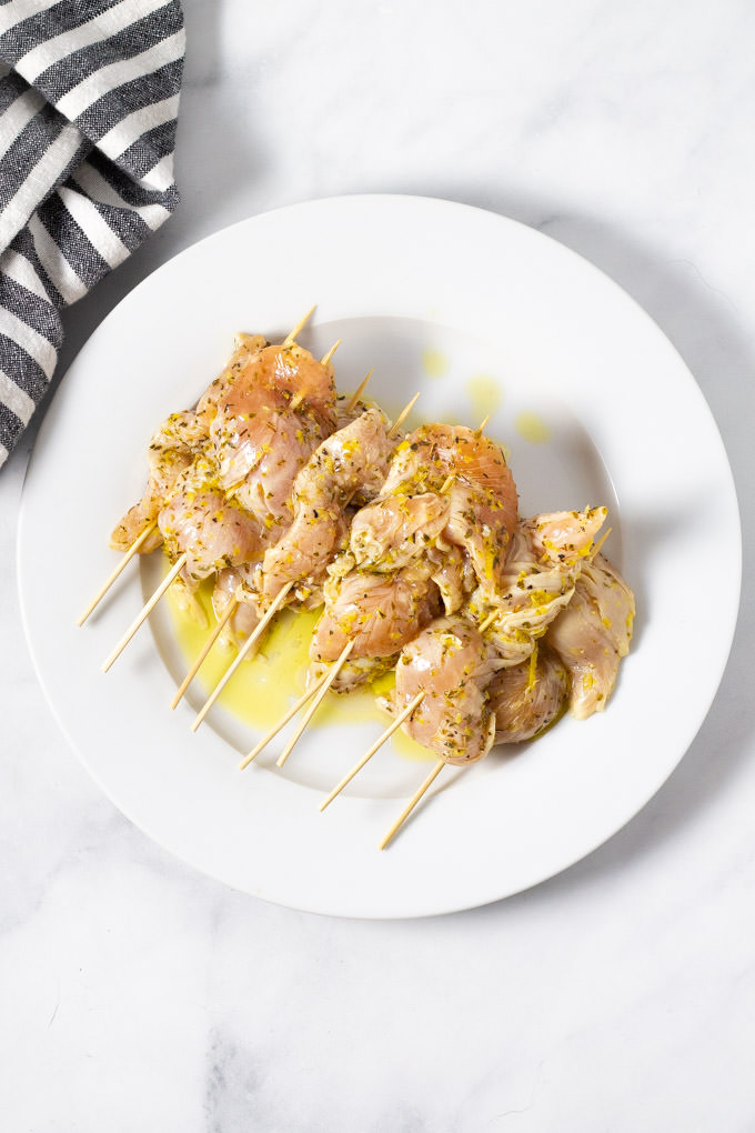 White plate filled with raw chicken kebabs