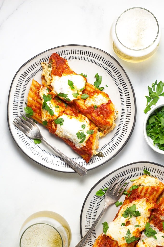Two plates filled with baked three cheese manicotti