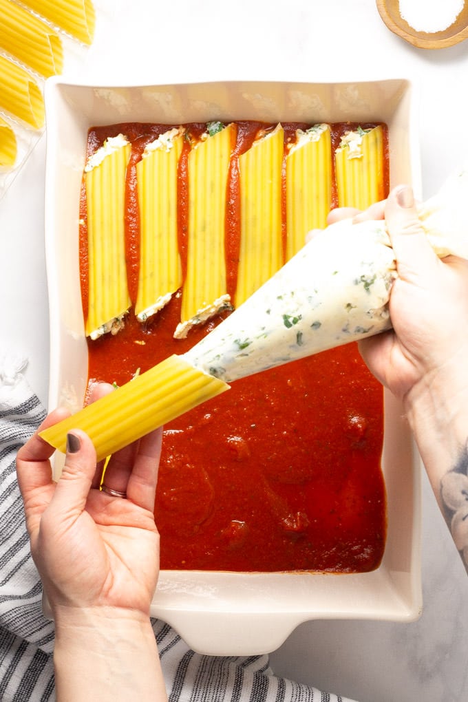 Overhead shot of manicotti being filled with ricotta cheese mixture