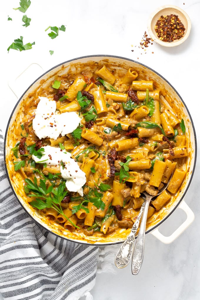 Large pan filled with sausage rigatoni garnished with fresh parsley