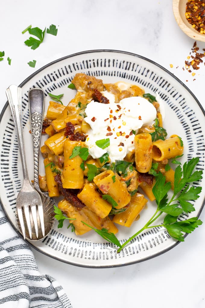Plate filled with sausage rigatoni garnished with fresh parsley