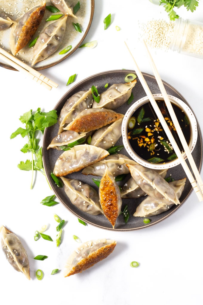 Vegan dumplings on a blue plate with soy sauce