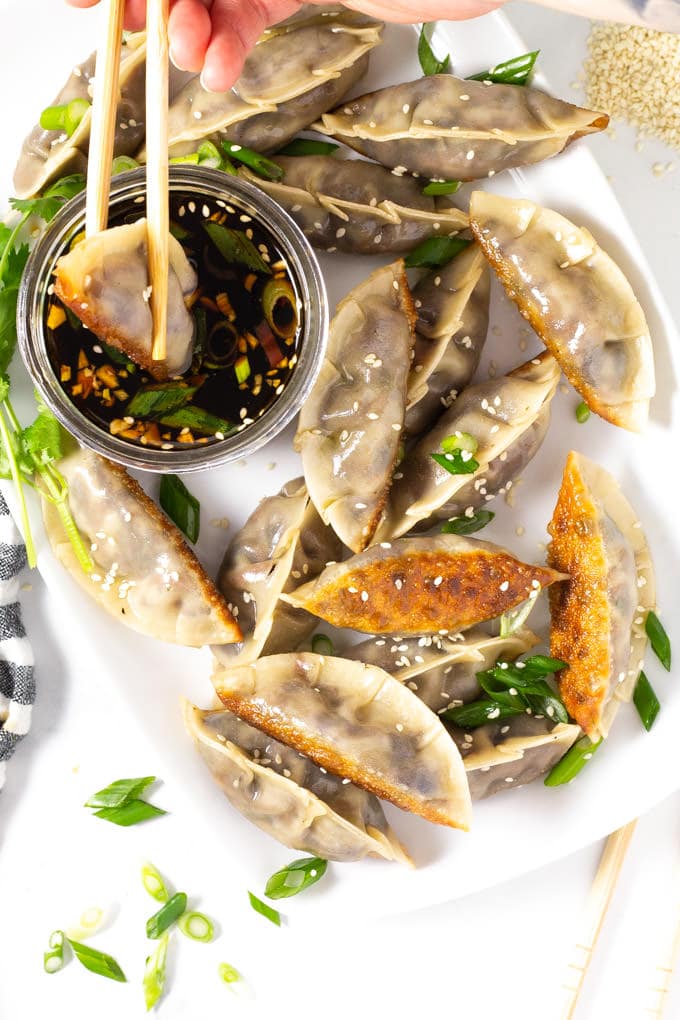Vegan dumpling being dipped into soy sauce