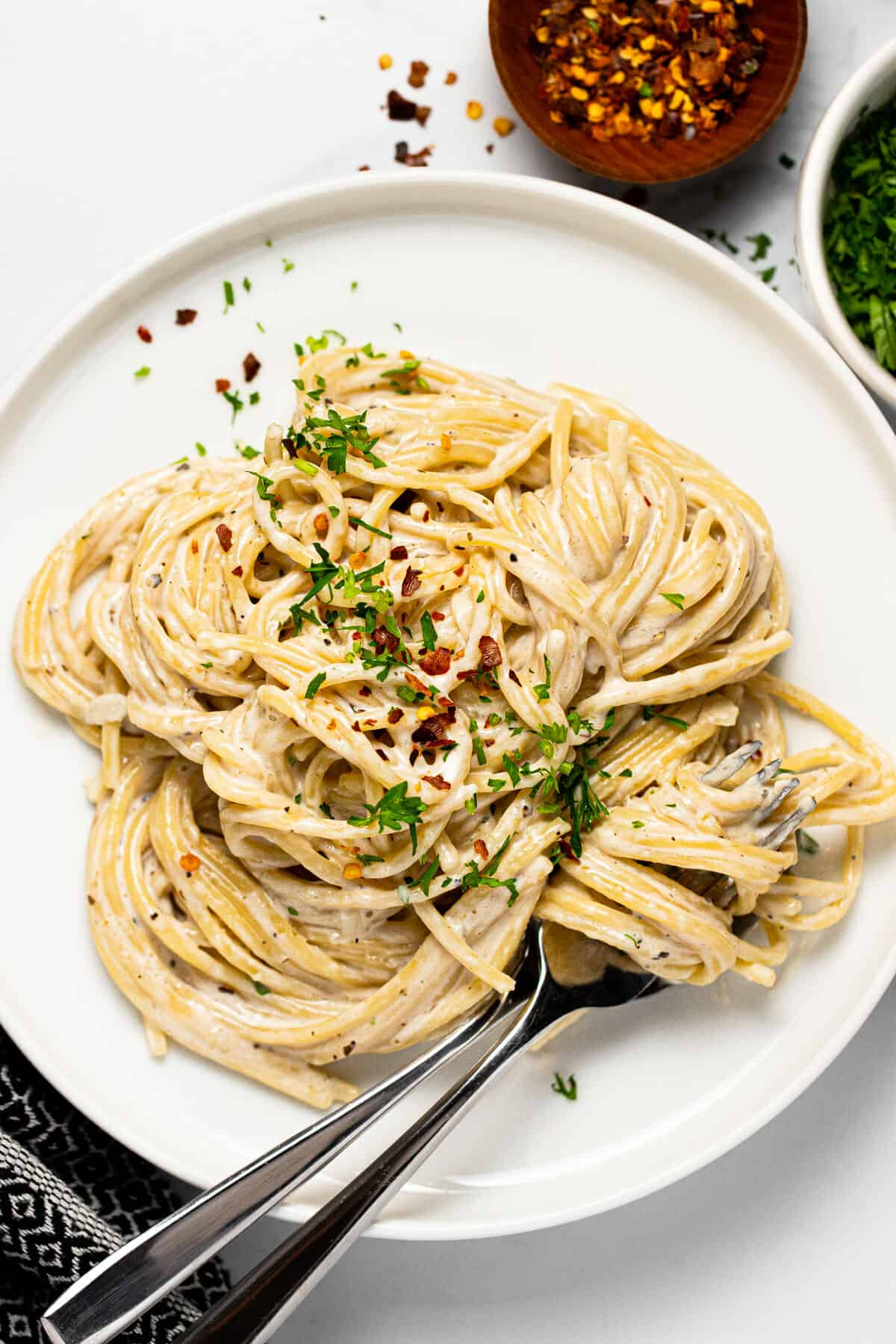 Large white plate filled with garlic Parmesan pasta topped with parsley