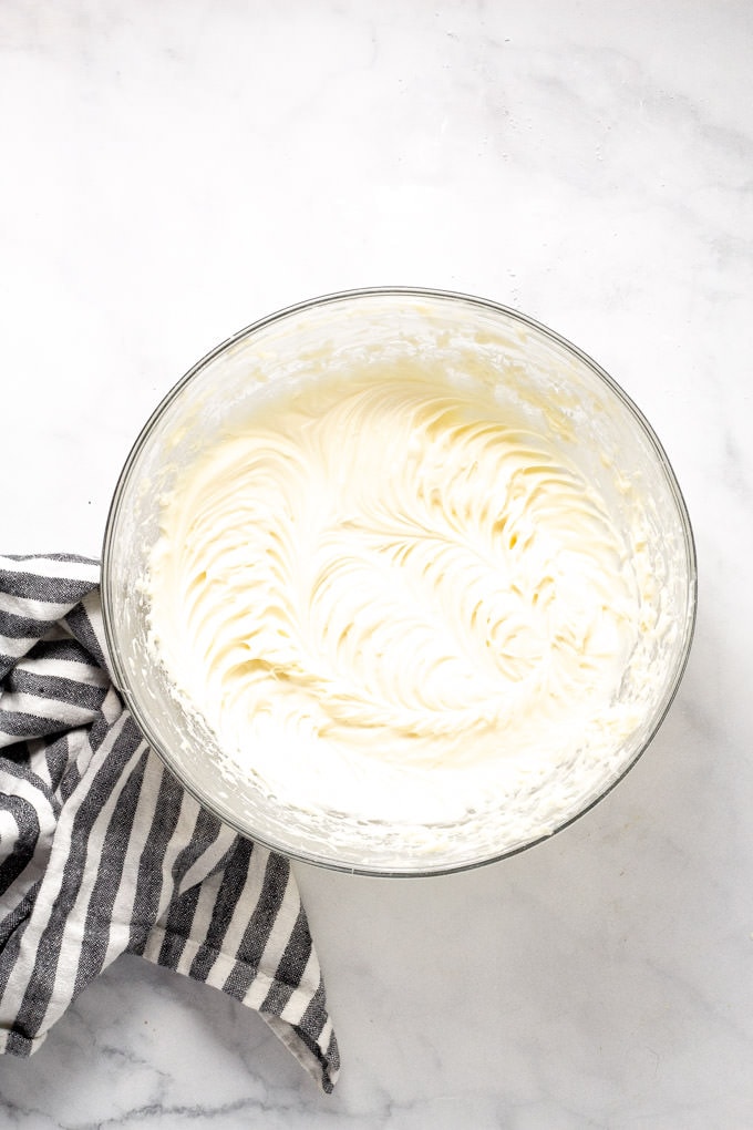 Overhead shot of prepared cream cheese frosting for homemade cinnamon rolls
