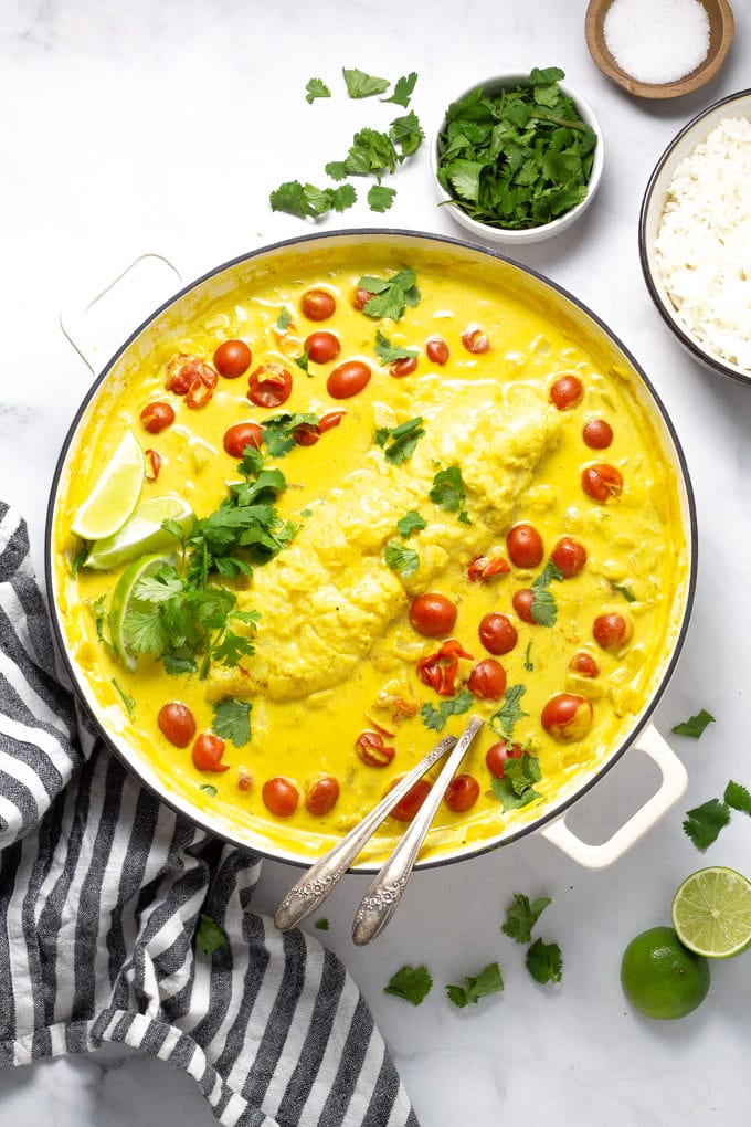 Overhead shot of a pot filled with tomato coconut curried cod garnished with fresh cilantro