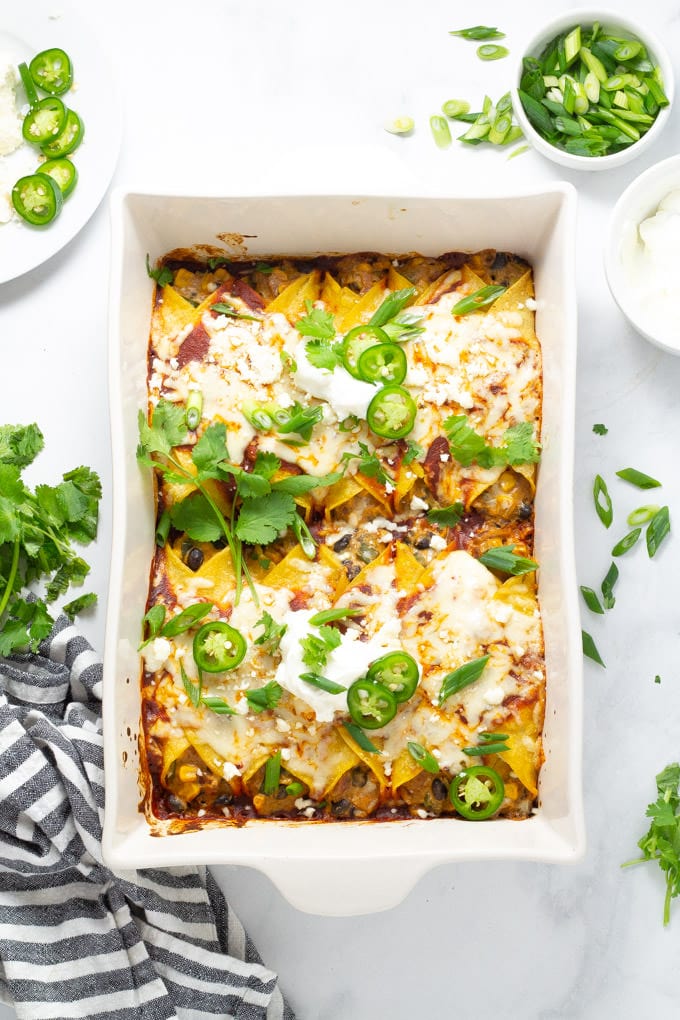 Overhead shot of a pan of veggie enchiladas garnished with jalapeno and cilantro