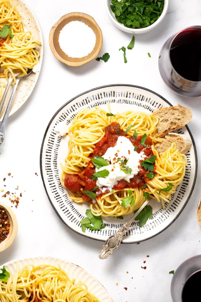 Overhead shot of three plates of spaghetti with homemade pasta sauce and fresh parsley