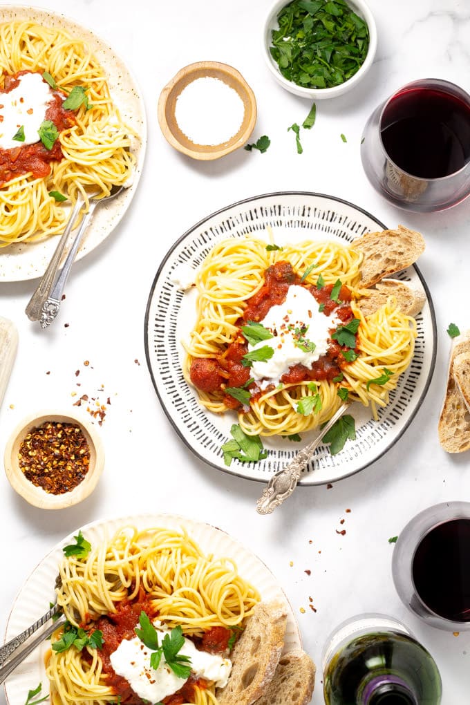Overhead shot of three plates of spaghetti with homemade pasta sauce and fresh parsley