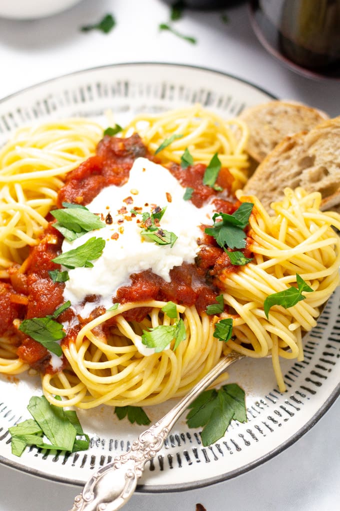 Close up shot of a plate of spaghetti with homemade pasta sauce and fresh parsley