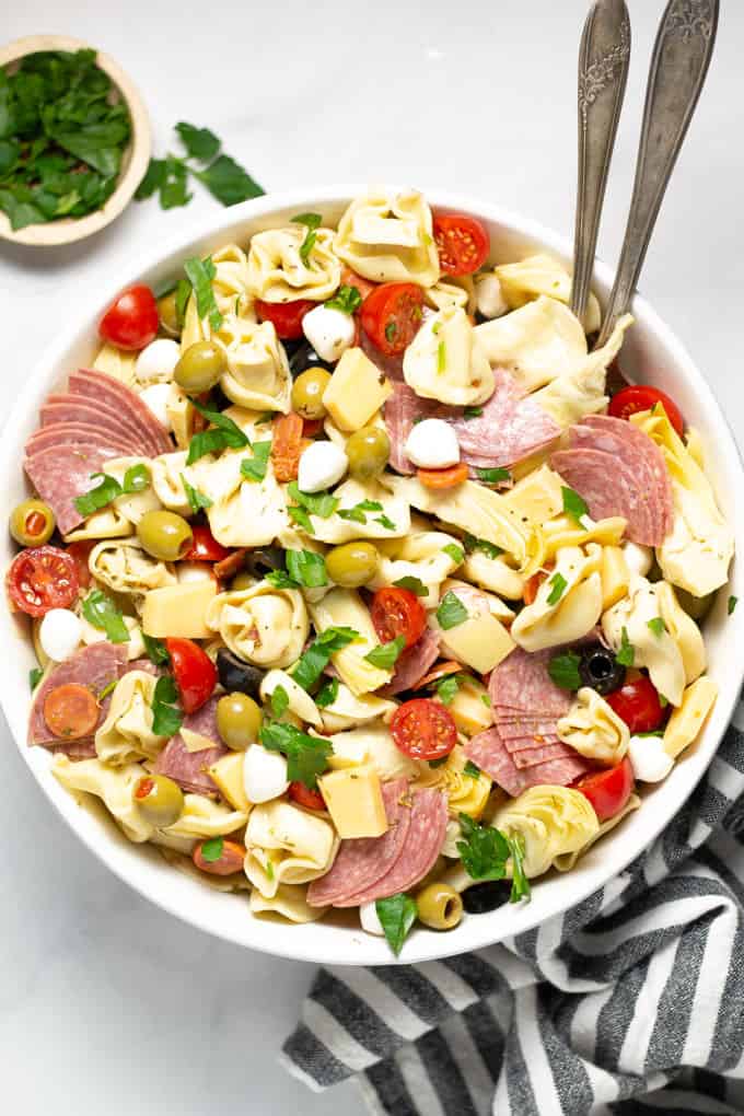 Overhead shot of a white bowl filled with antipasto pasta salad garnished with fresh parsley