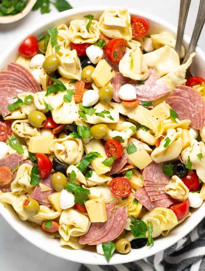 Close up shot of a white bowl filled with antipasto pasta salad