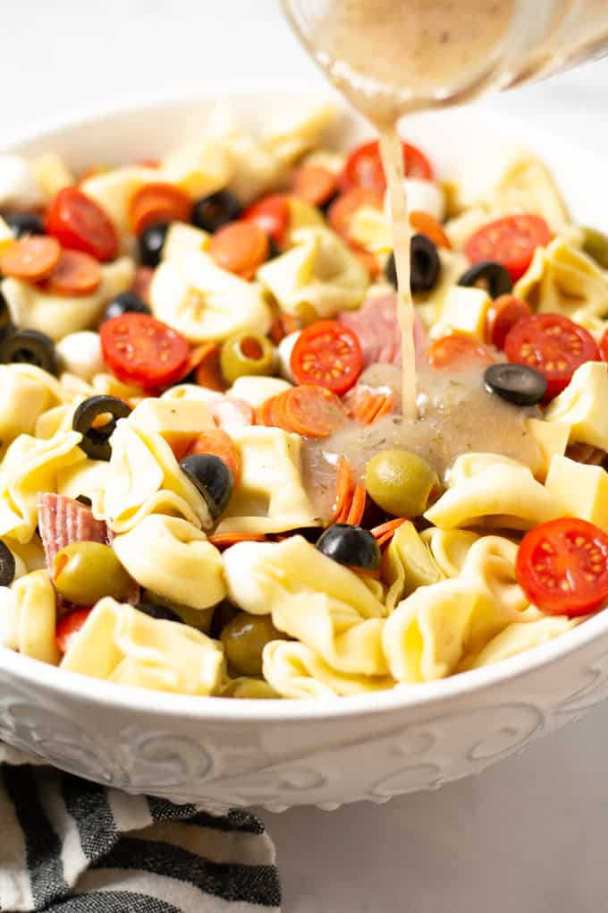 Close up shot of a white bowl filled with pasta salad loaded with meat and veggies