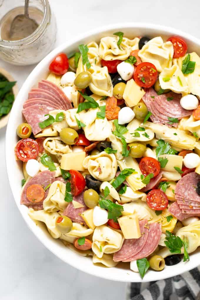 Overhead shot of a white bowl filled with antipasto pasta salad garnished with fresh parsley