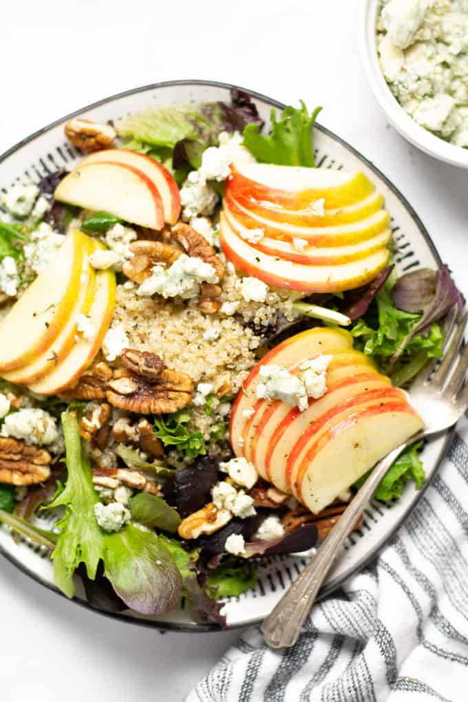 Close up shot of a meal prep salad filled with apple pecan and Gorgonzola on a bed of greens