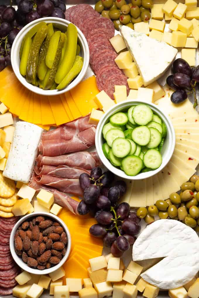 Overhead shot of a cheese board filled with cheese meat veggies and fruit