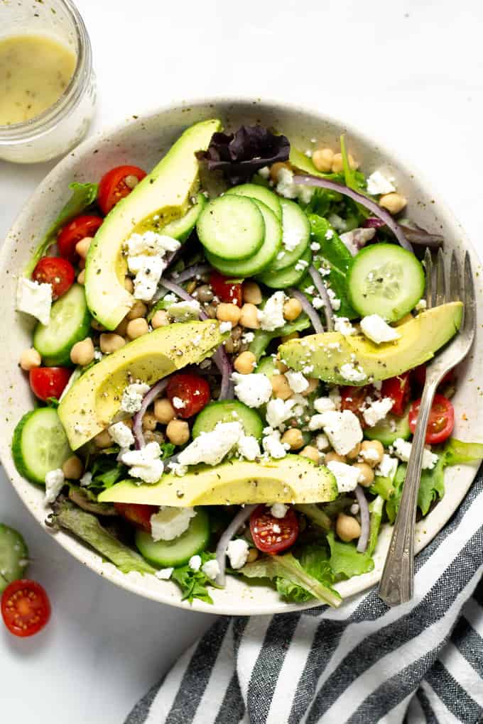 Overhead shot of a meal prep salad loaded with avocado cucumber red onion and tomatoes