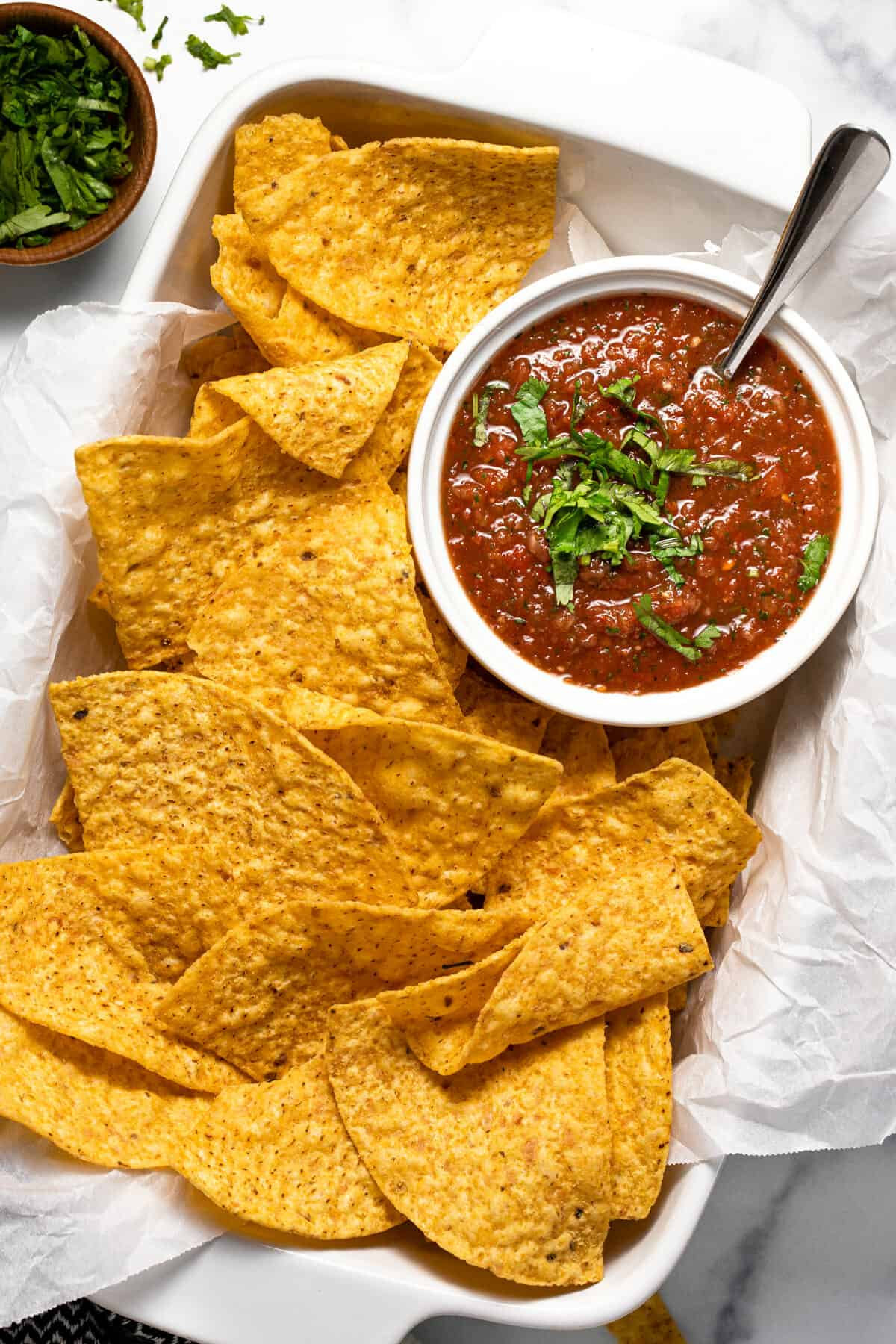 Large white dish filled with tortilla chips and a bowl of homemade salsa