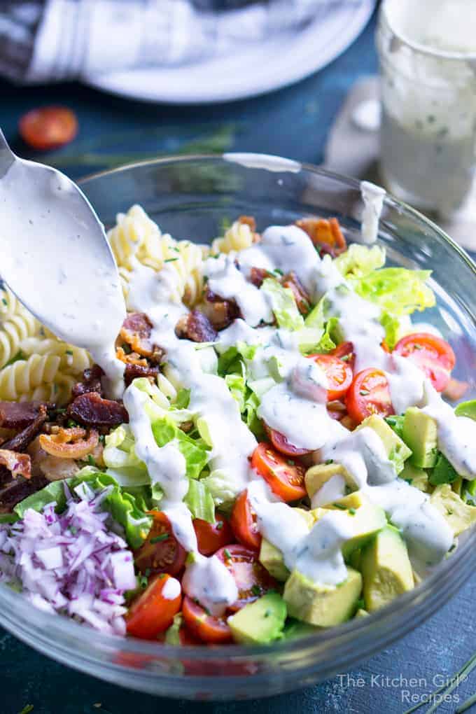 Close up shot of a BLT salad being drizzled with creamy dressing