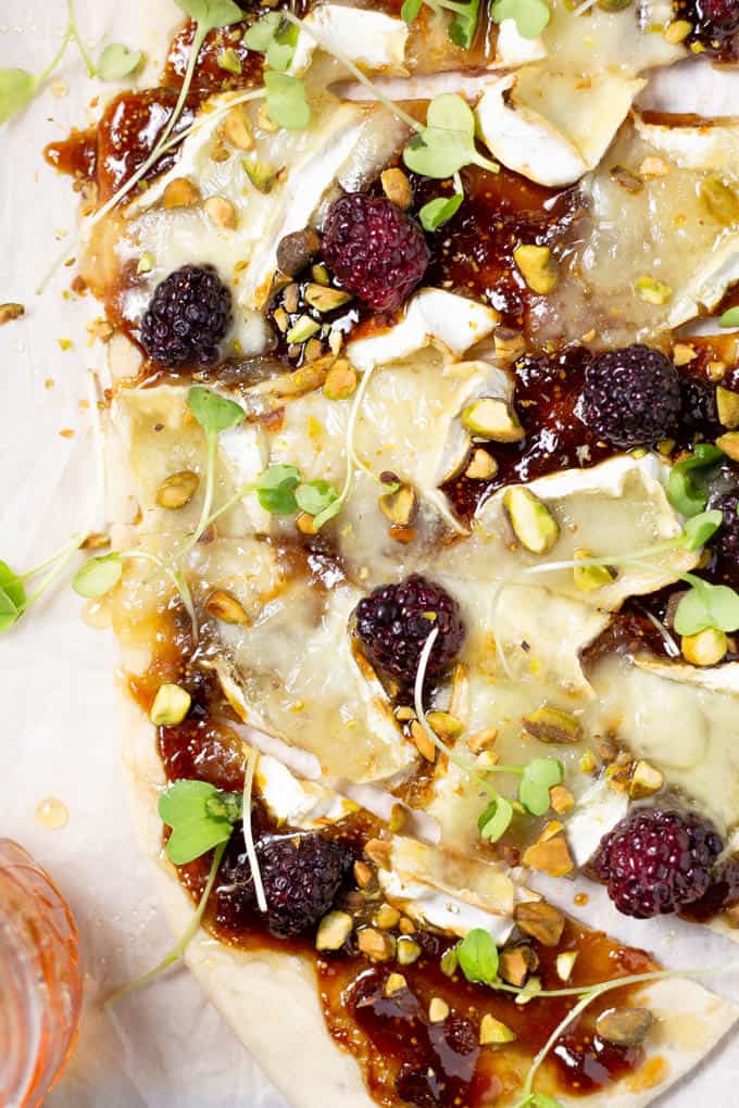 Overhead shot of a brie and blackberry flatbread pizza garnished with microgreens