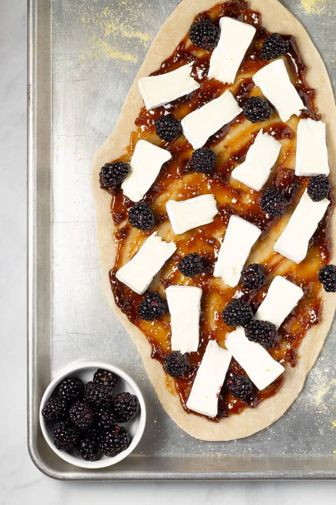 Overhead shot of a flatbread crust topped with fig jam brie cheese and blackberries