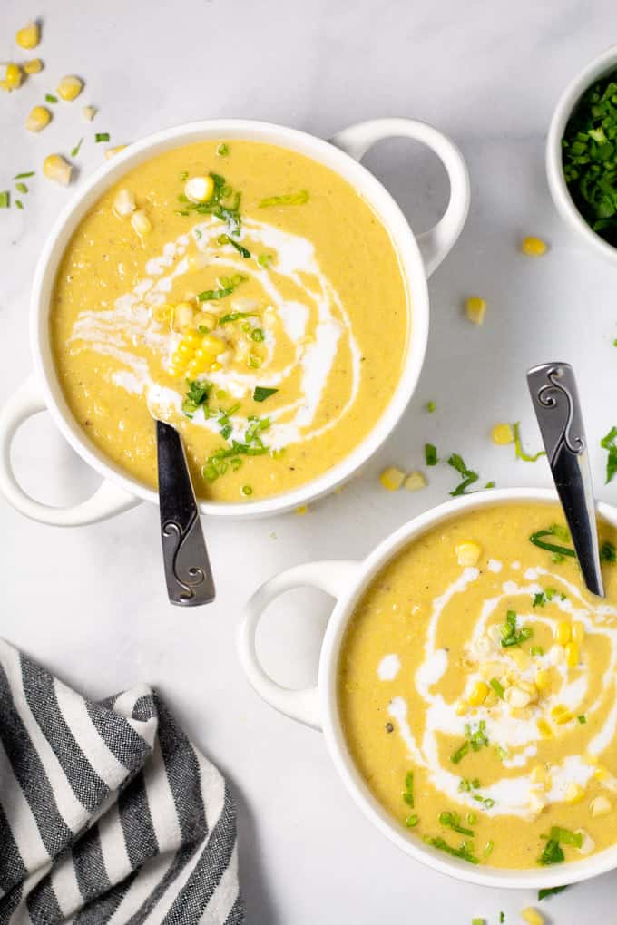 Overhead shot of two bowls of corn chowder garnished with fresh chopped parsley
