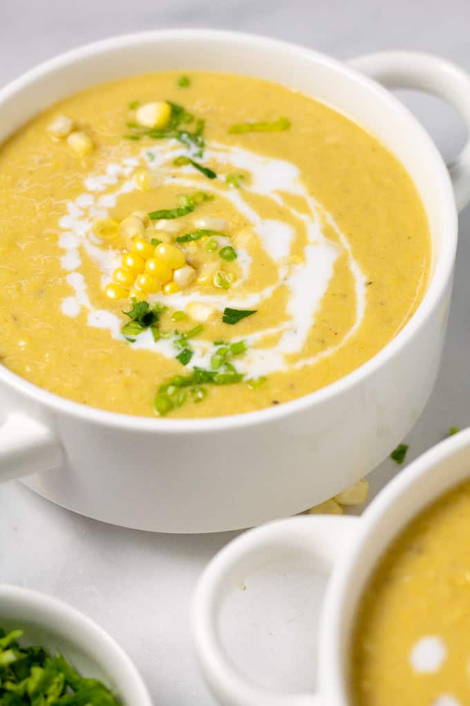 Close up shot of a bowl of corn chowder garnished with fresh chopped parsley