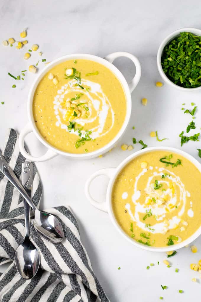 Overhead shot of two bowls of corn chowder garnished with fresh chopped parsley
