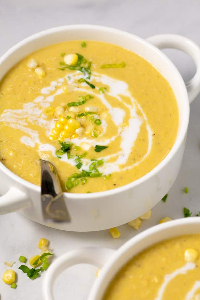 Close up shot of a bowl of corn chowder garnished with fresh chopped parsley