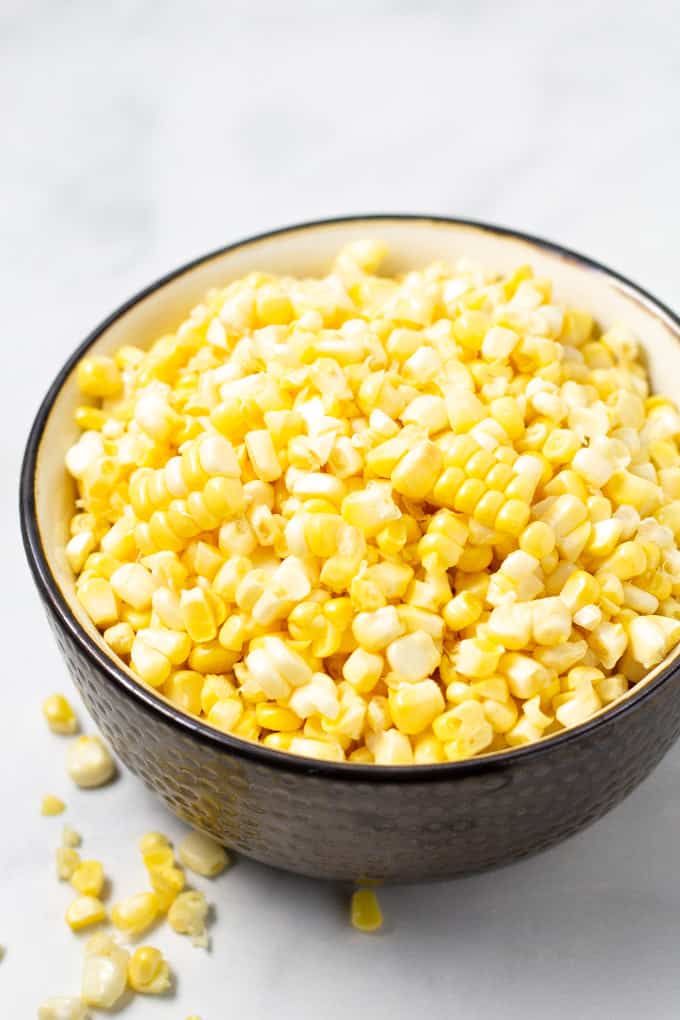 Close up shot of a bowl of corn kernels on a marble counter top