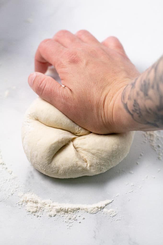 White marble counter top with a hand kneading flatbread dough