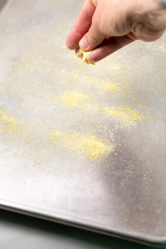 A baking sheet being dusted with cornmeal