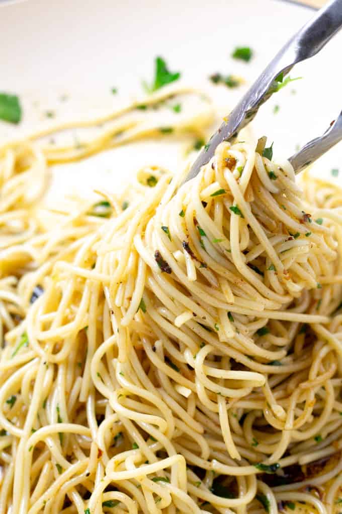 Close up shot of spaghetti being tossed in a lemon butter sauce with parsley