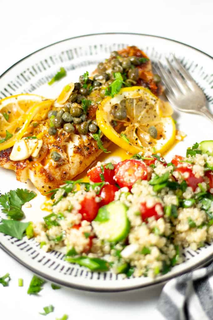 A plate filled with quinoa tabbouleh and Mediterranean cod garnished with fresh parsley