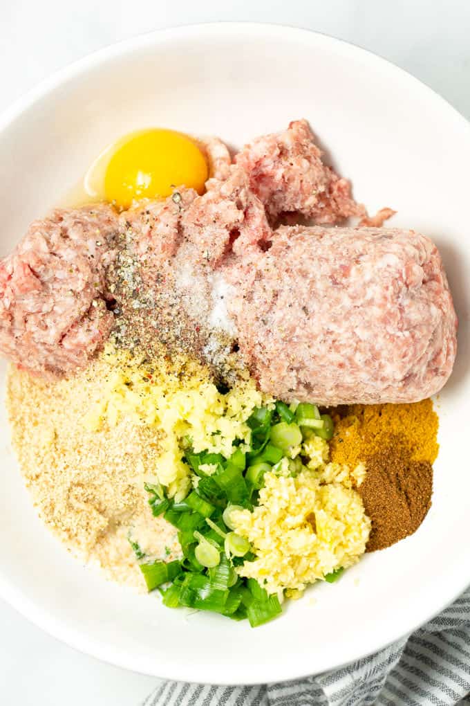 Overhead shot of a white bowl filled with ingredients to make pork meatballs