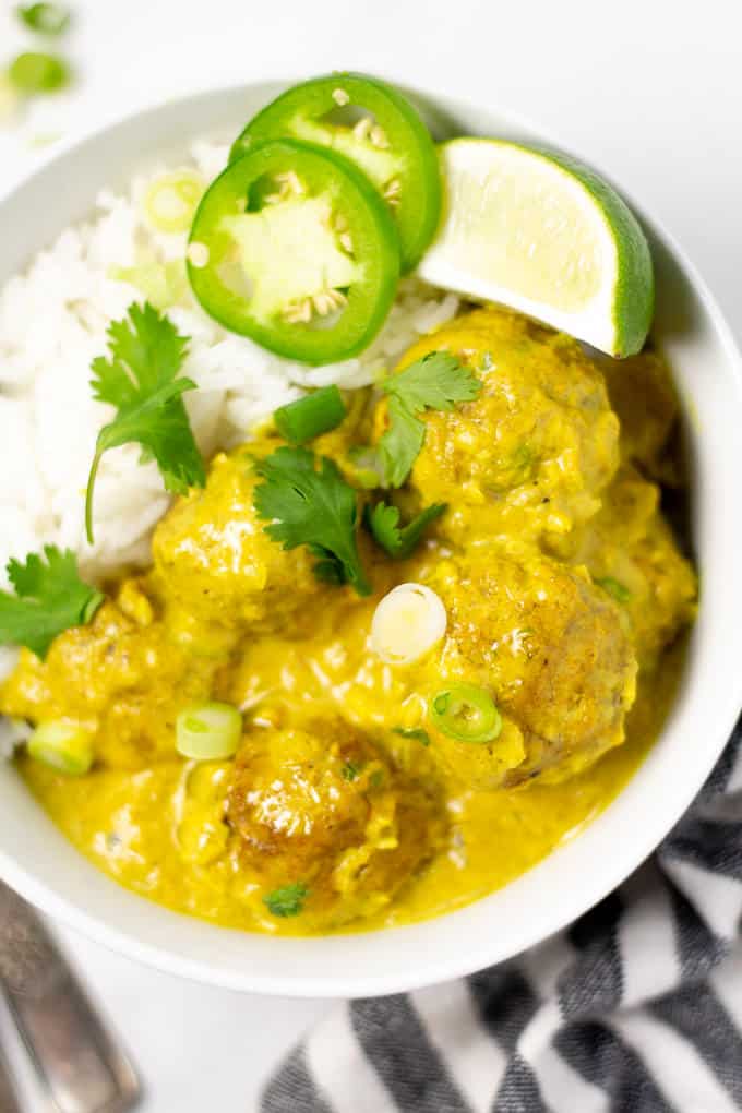 Close up shot of curried pork meatballs garnished with fresh cilantro on a bed of white rice