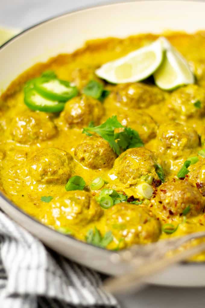 Close up shot of a pan of curried pork meatballs garnished with fresh cilantro