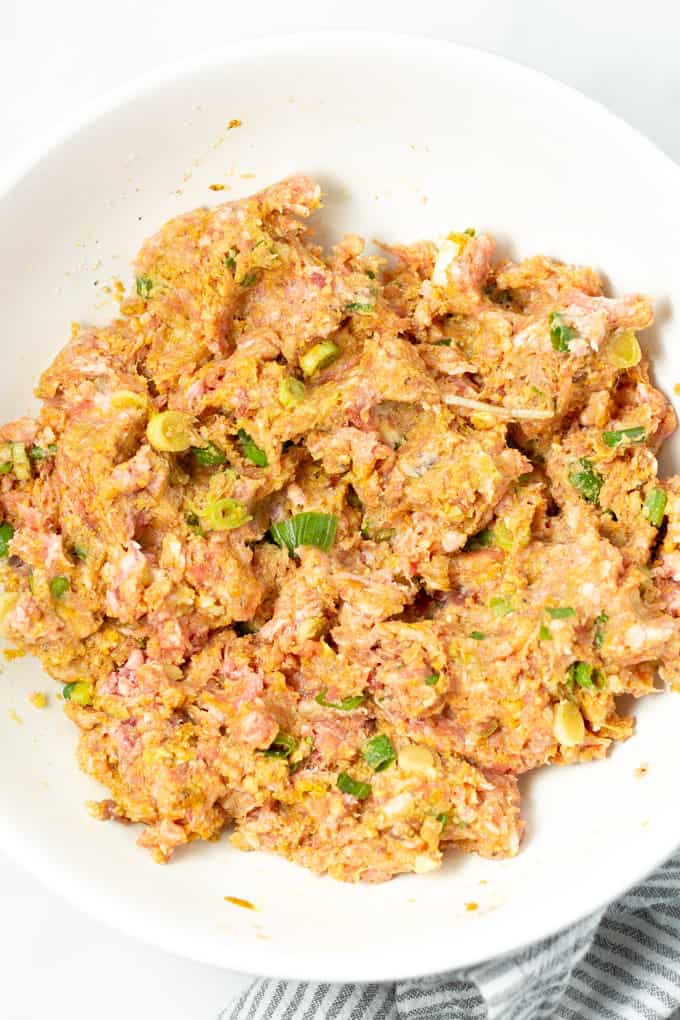 White bowl filled with the ingredients mixed together to make pork meatballs
