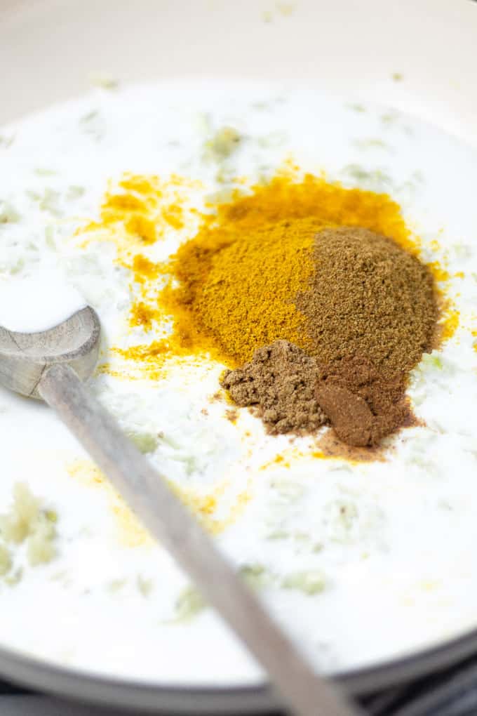 Close up shot of a pan with onions coconut milk and spices