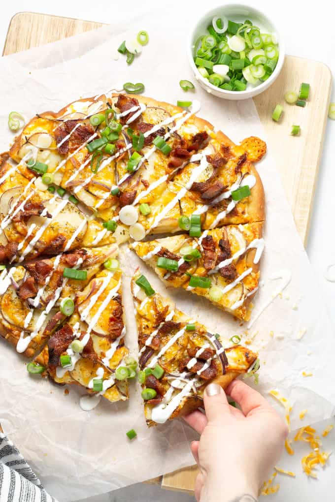 Overhead shot of a baked potato pizza garnished with sour cream and green onion