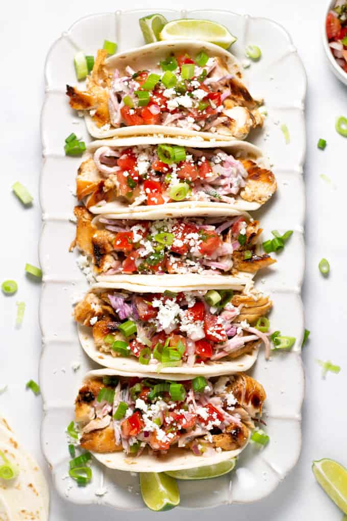 White platter filled with chicken tacos dressed with pico de gallo