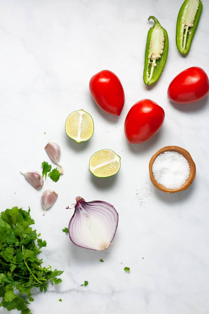White marble counter top with ingredients for make pico de gallo