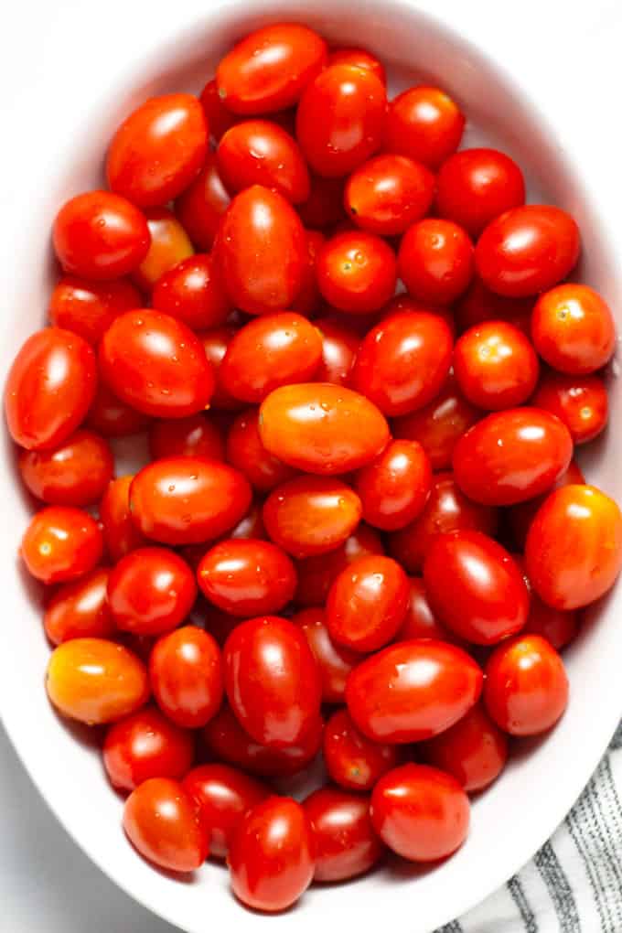 Close up overhead shot of a white platter filled with freshly washed grape tomatoes 