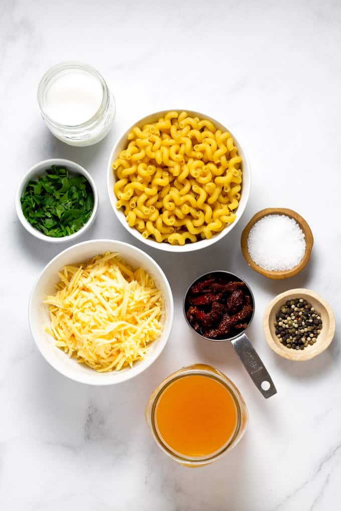 White marble counter top with the ingredients in bowls to make smoked gouda mac and cheese